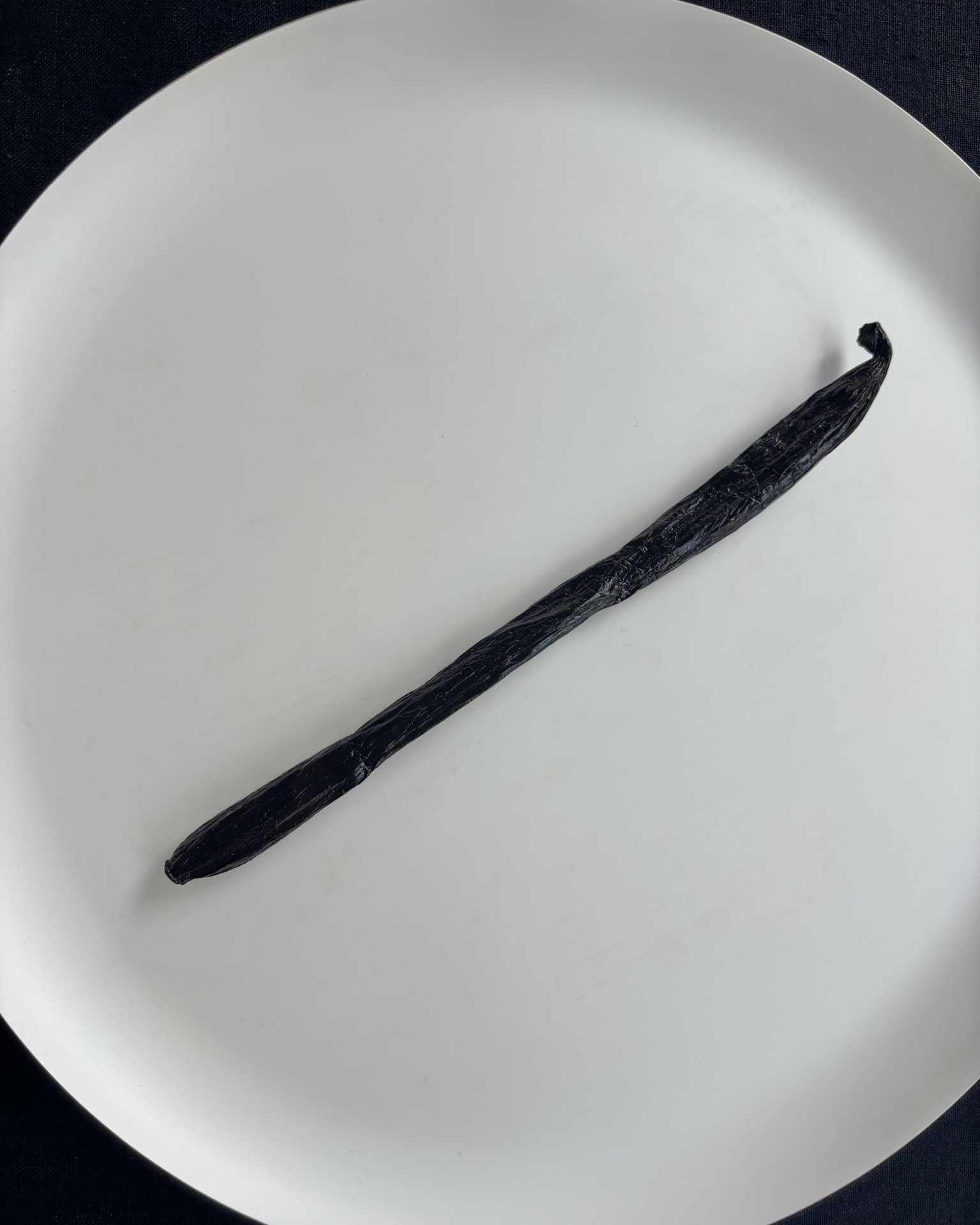 Gousse entière de vanille Pompona de Madagascar présentée sur une assiette